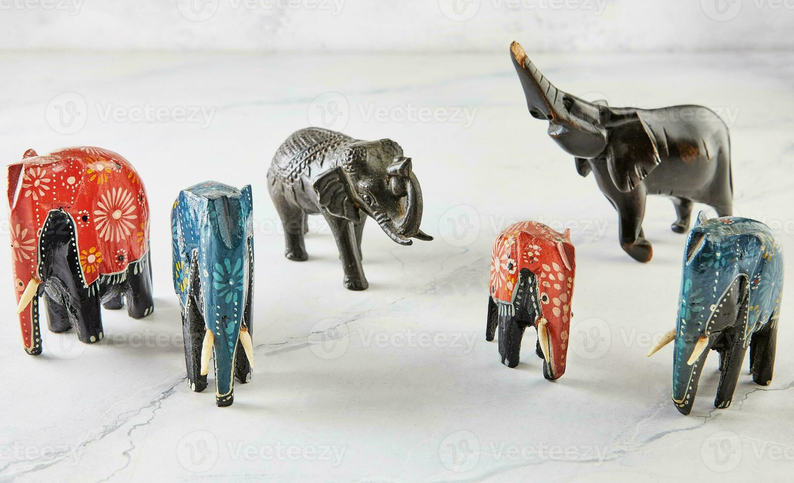 Elephant figurines of different colors and shapes on white marble photo