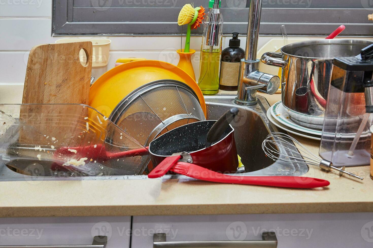 Mountain of unwashed dishes in the sink and around in home kitchen photo