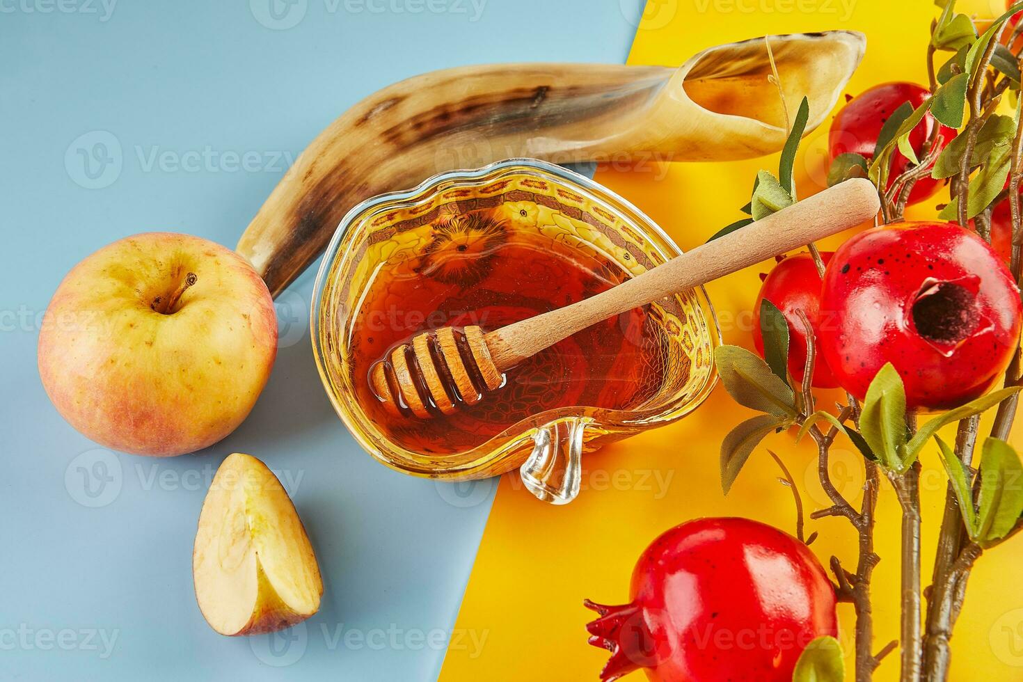 Rosh hashanah - jewish new year holiday concept. Bowl in the form of an apple with honey, apples, pomegranates, shofar on yellow-blue background photo