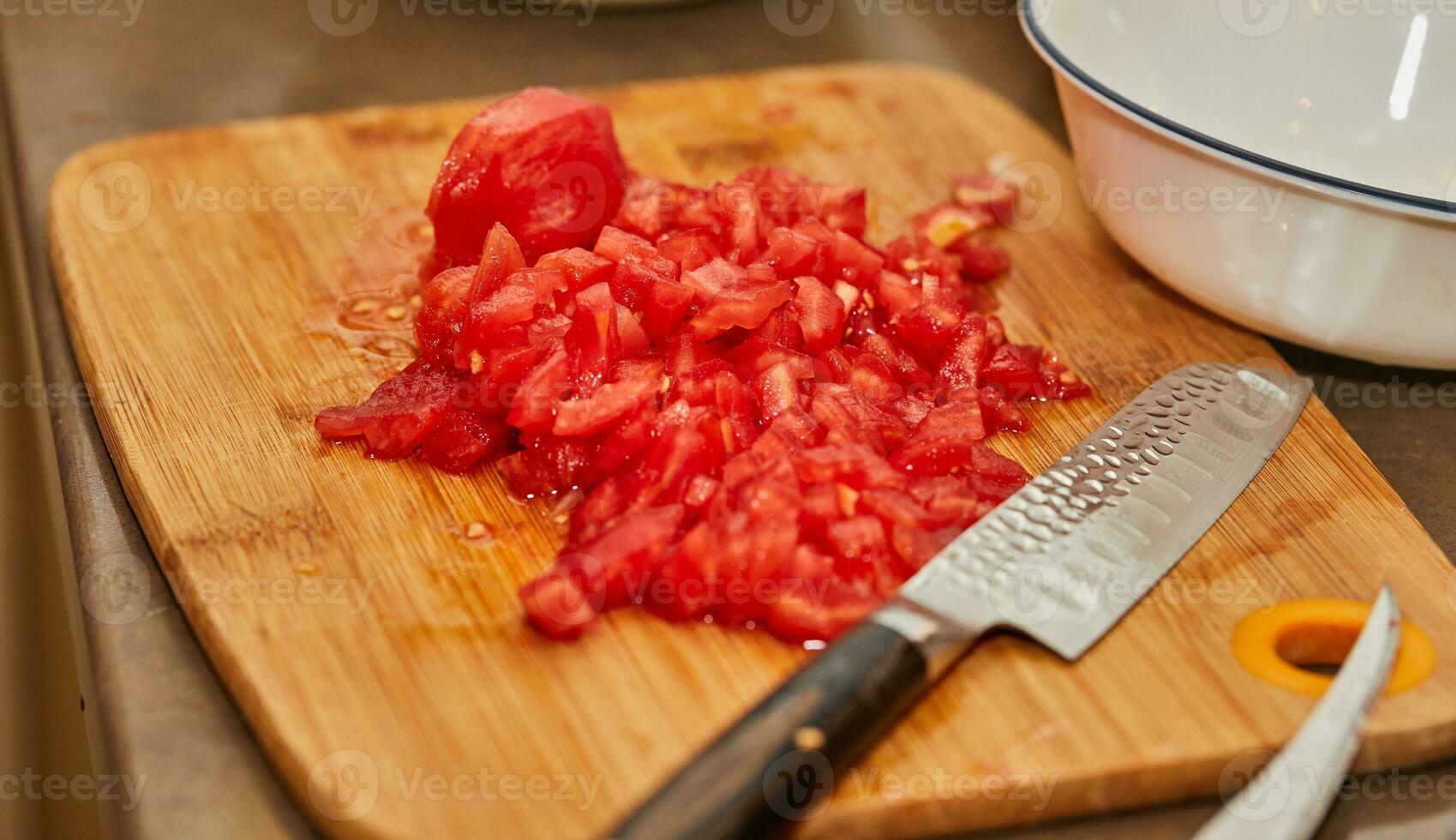 Chef cuts the tomatoes into small cubes for cooking photo