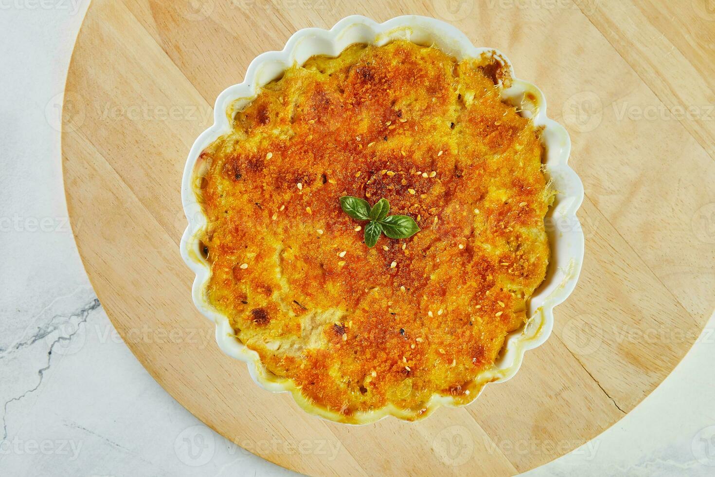 Potato and pumpkin gratin in white bowl on wooden stand photo