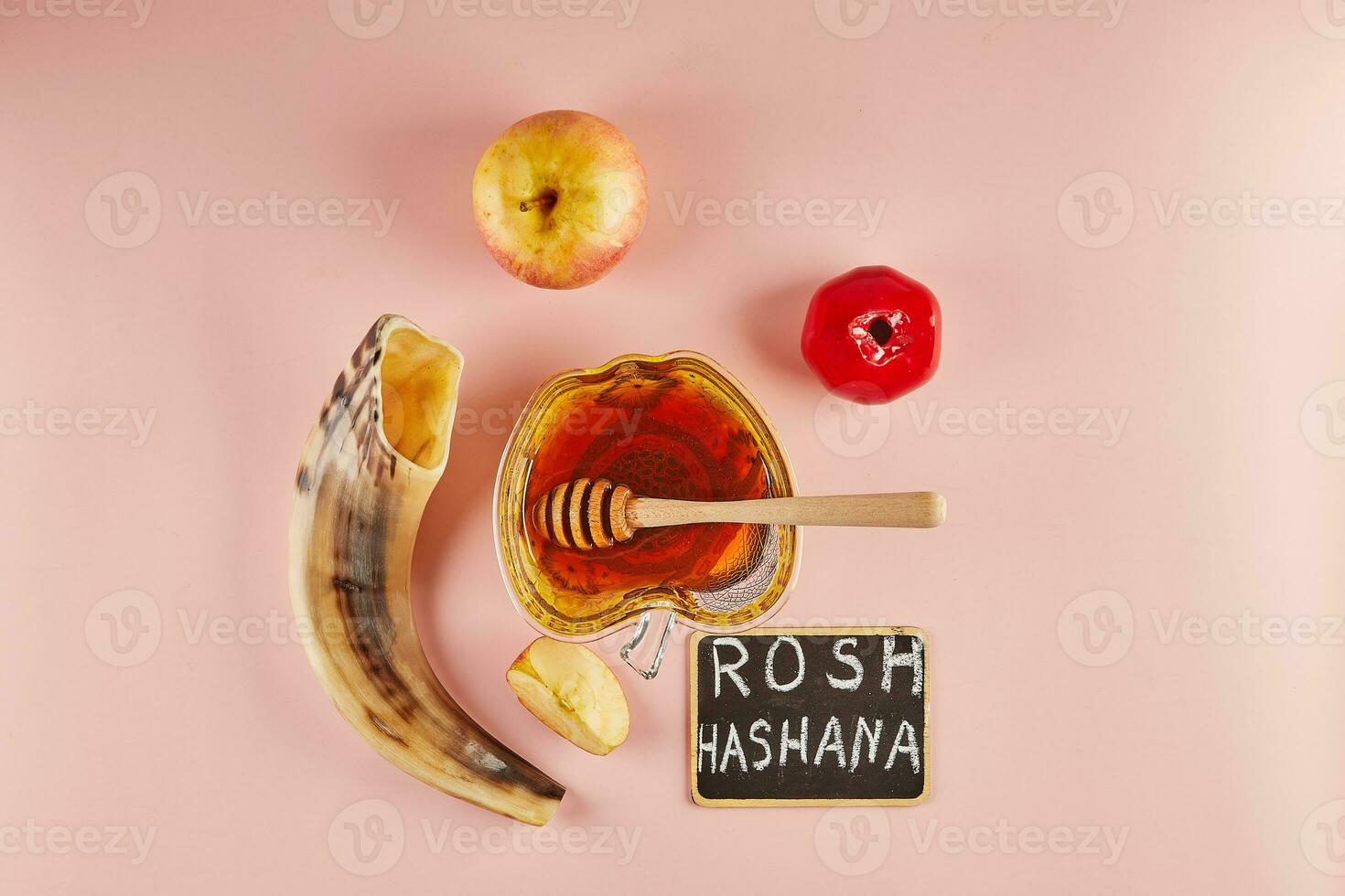 Rosh hashanah lettering - jewish new year holiday concept. Bowl in the shape of an apple with honey, apples, pomegranates, shofar on pink background. photo