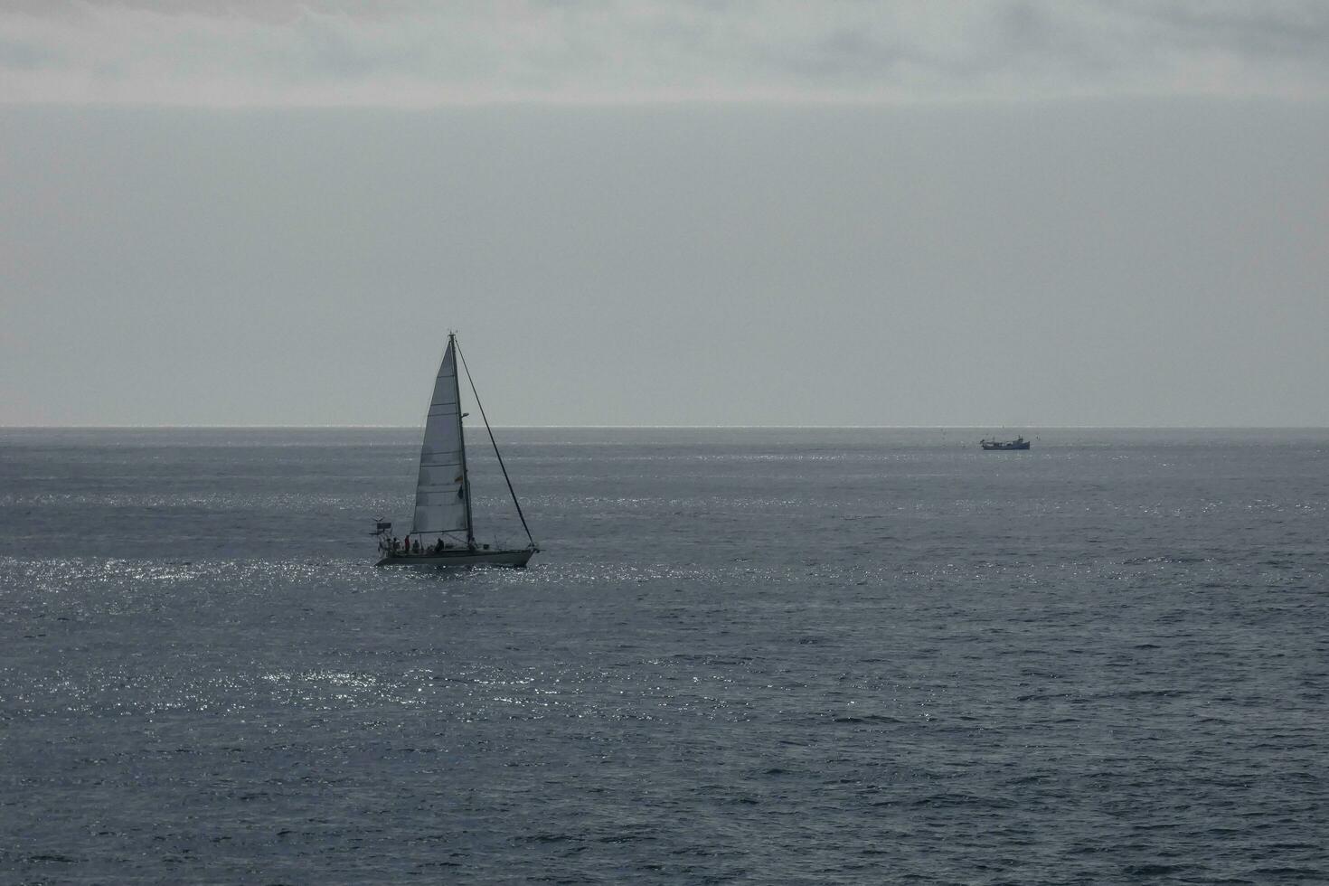 Sailboat with sail unfurled, sailing on the calm sea at sunset. photo