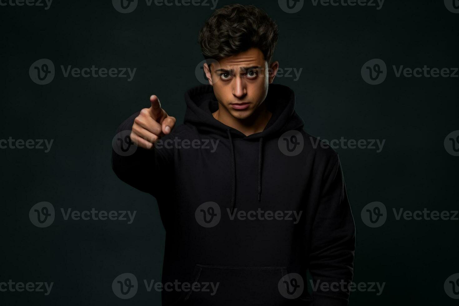 Young Hindu man in black hoodie happily points to blank space for your ad photo