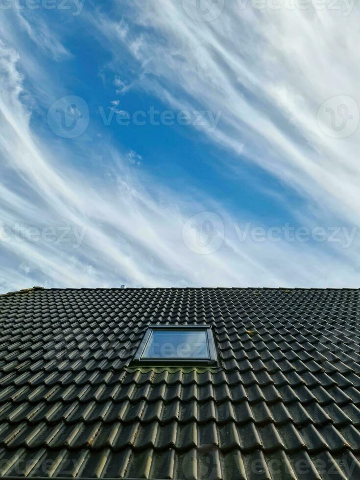 ventana de techo abierta en estilo velux con tejas negras. foto