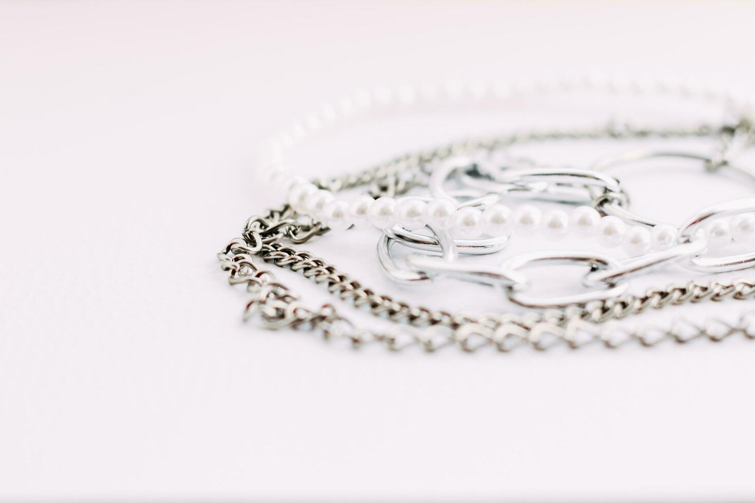 A necklace of white beads with chains of jewelry on a white aesthetic background. photo