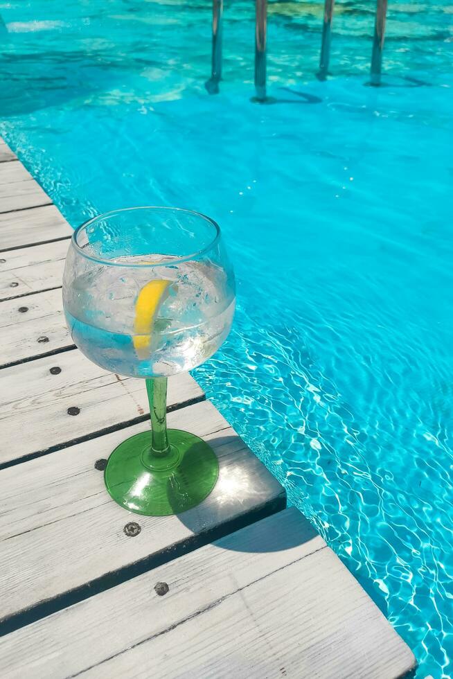 Cocktail with lemon tonic on blue pool background photo