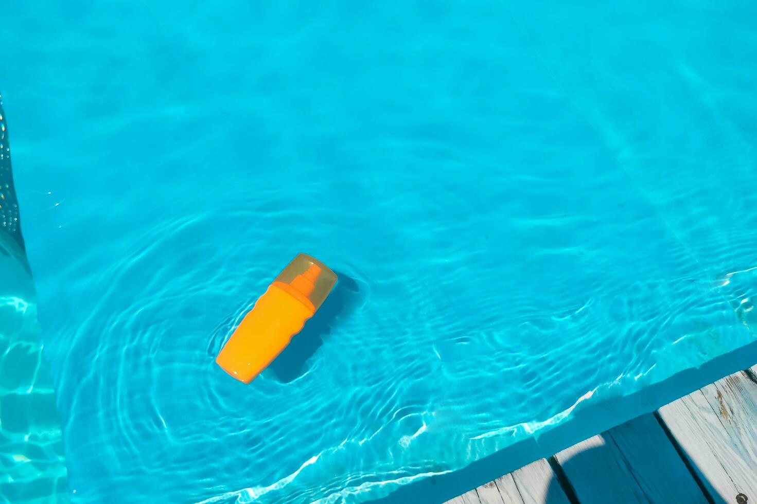 Spray sunscreen stands on the background of the pool photo