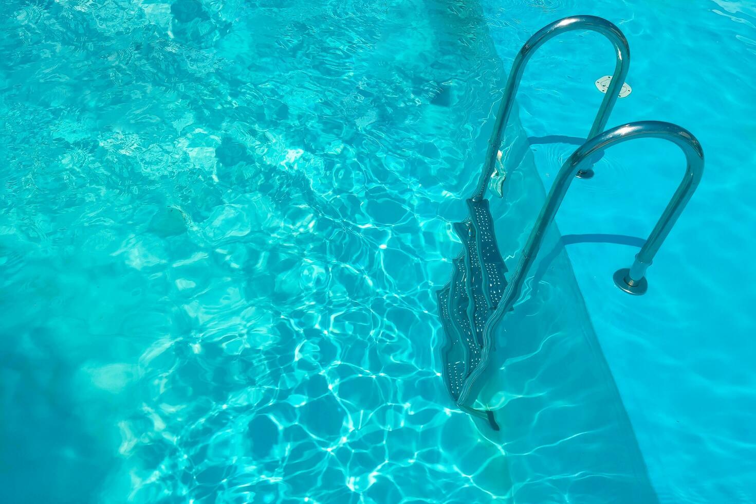 Staircase in the swimming pool with blue water in the background photo