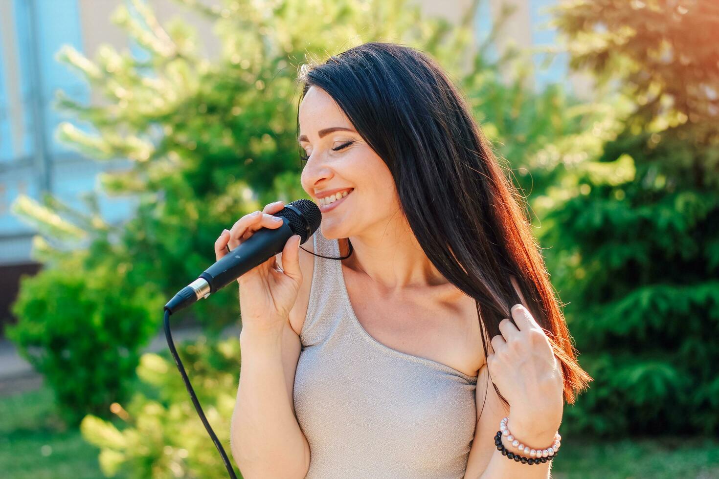 Woman vocalist with dark hair in a dress sings into a microphone photo