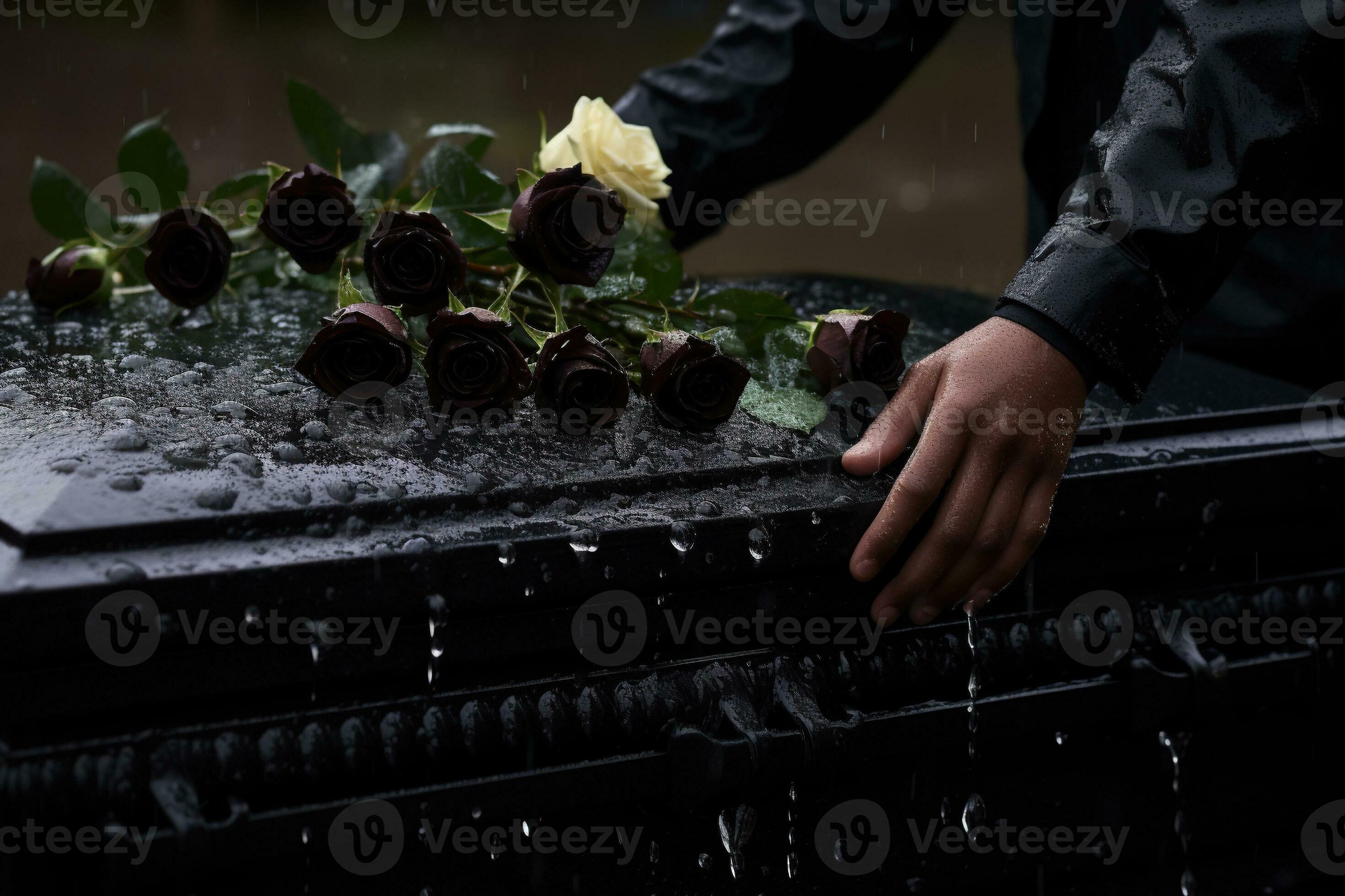 closeup of a funeral casket at a cemetery with flowers in the rain,hand