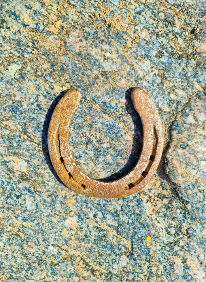 A rusty horseshoe on a stone background texture. photo