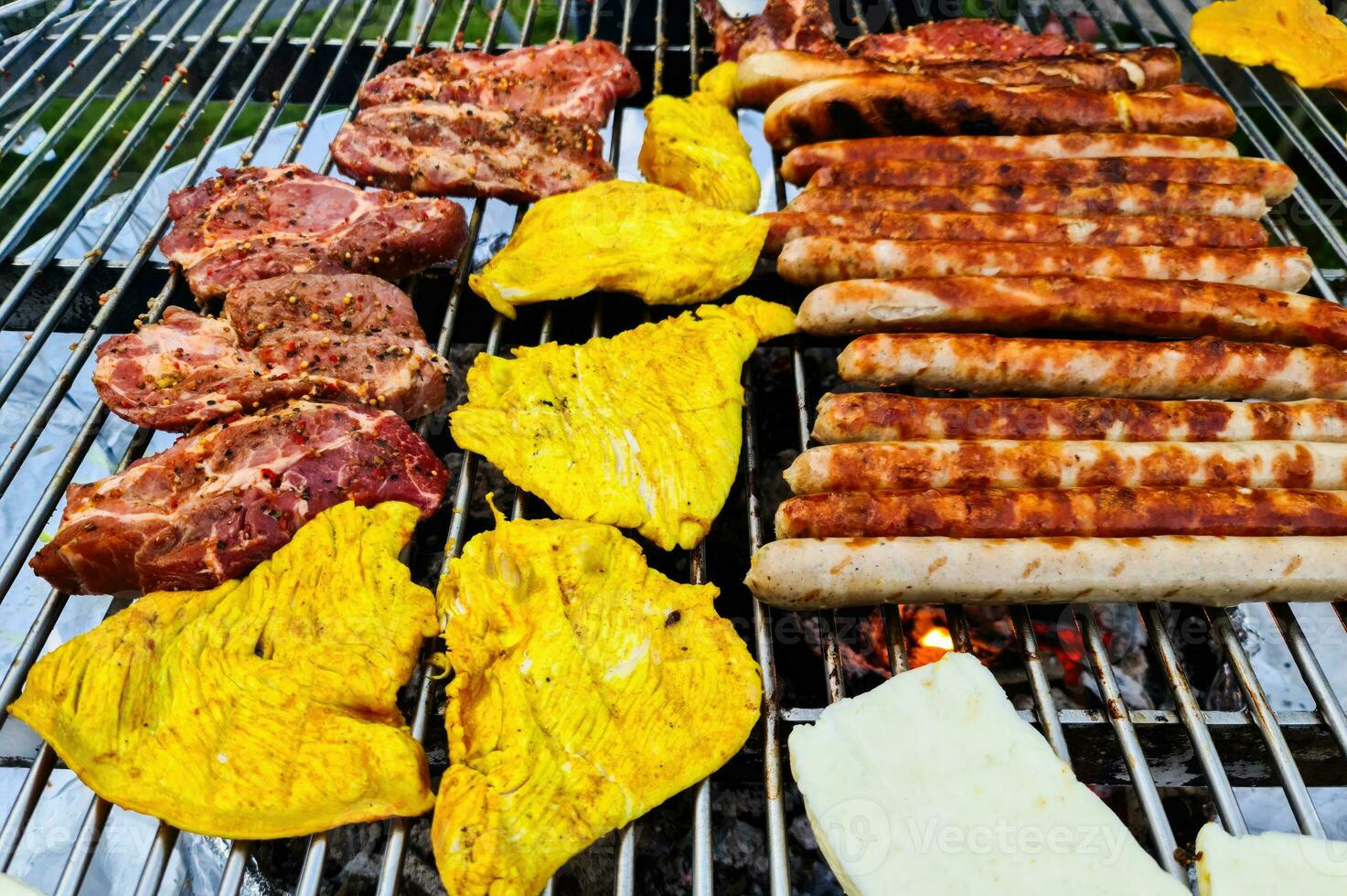 View of a grill with many sausages and meat that are turned regularly. photo