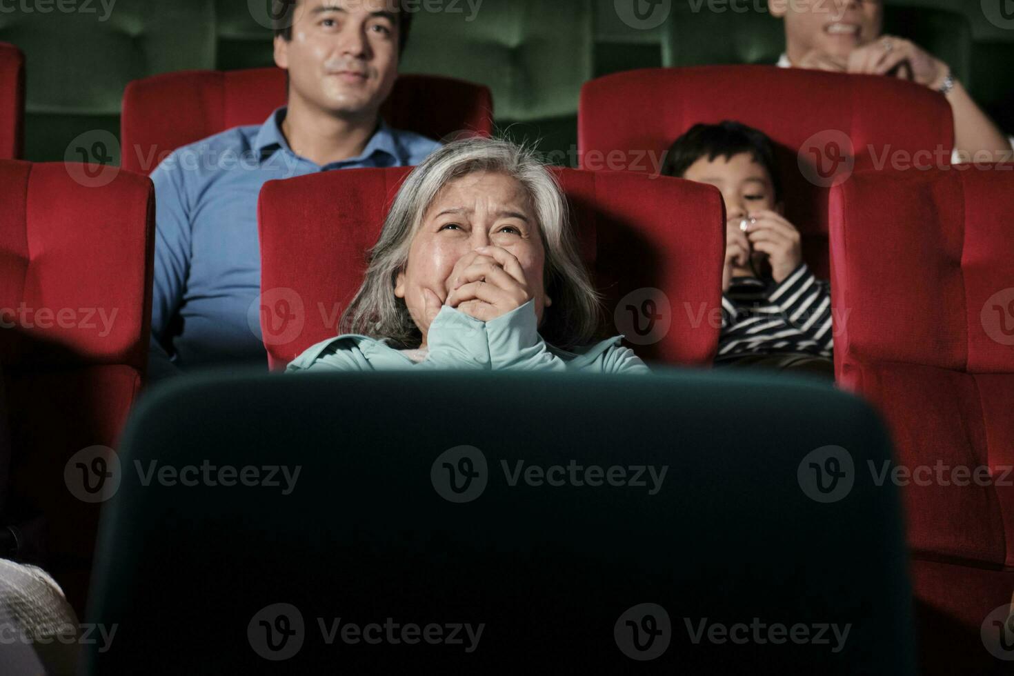 Various people in theater. Senior Asian woman and multiracial audiences are scared of watching thriller and horror cinema, frightened together of movie, and entertainment lifestyle with film art show. photo