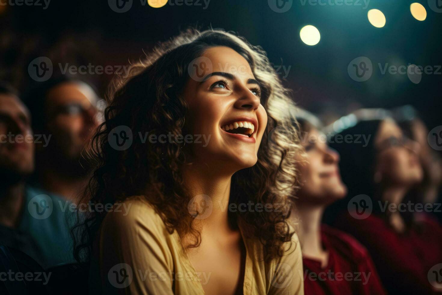 A woman joins a lively theater audience cheerfully clapping and enjoying the show photo