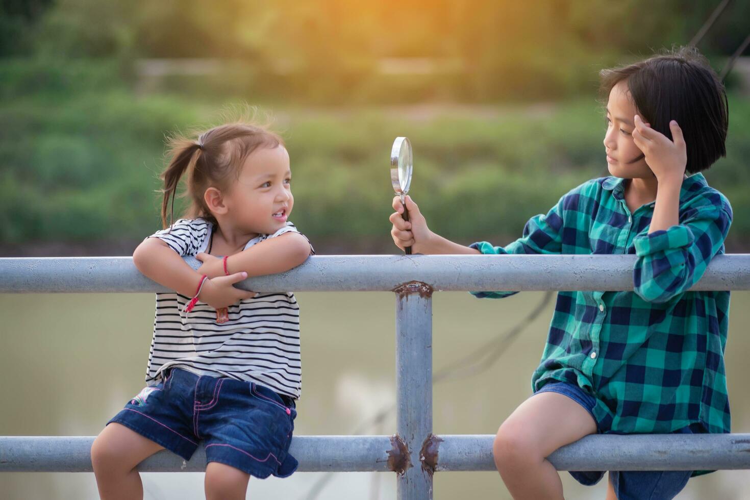 Asian little girl is using magnifying glass to play in the park.SSTKHome photo