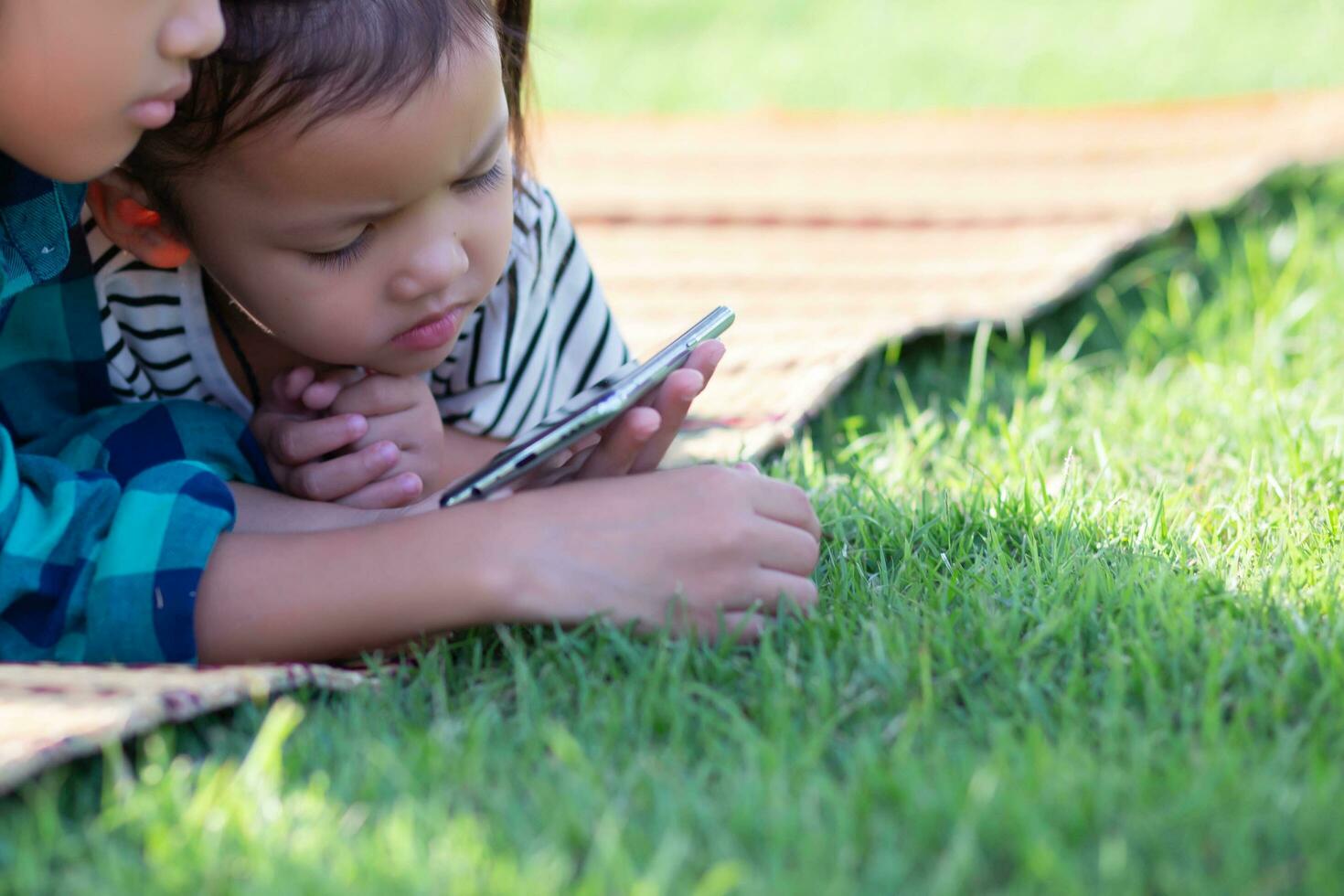Two young girls lying on the lawn looking at their phones, summer, golden hour, sunset. SSTKHome photo