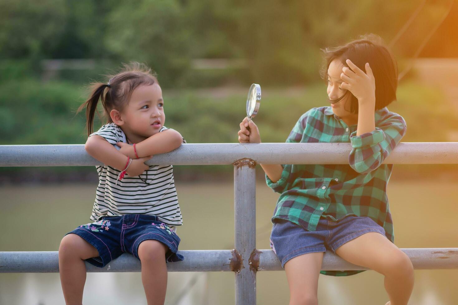 Asian little girl is using magnifying glass to play in the park.SSTKHome photo