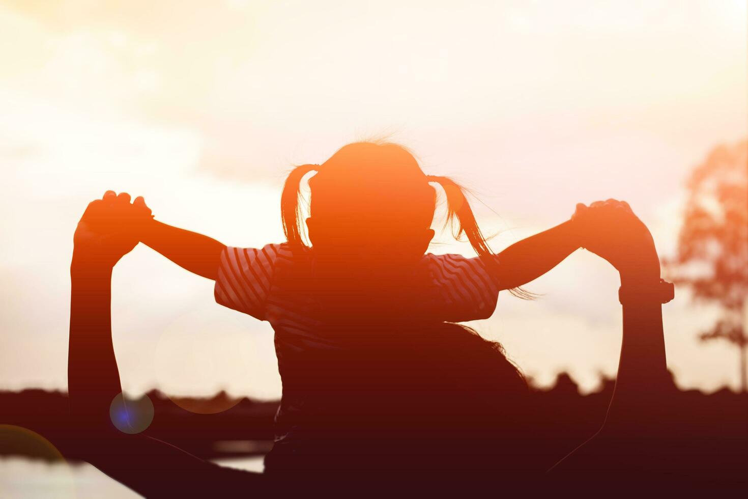 A silhouette of a happy young mother harmonious family outdoors. laughing and playing in the summer on the sunset background.SSTKHome photo