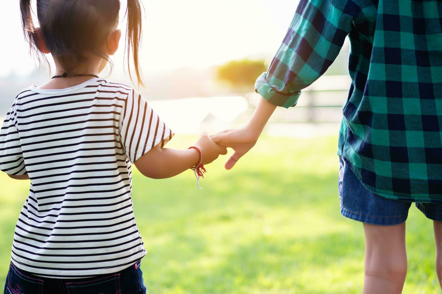 Profile view of cute kids run in park hold hands.SSTKHome photo