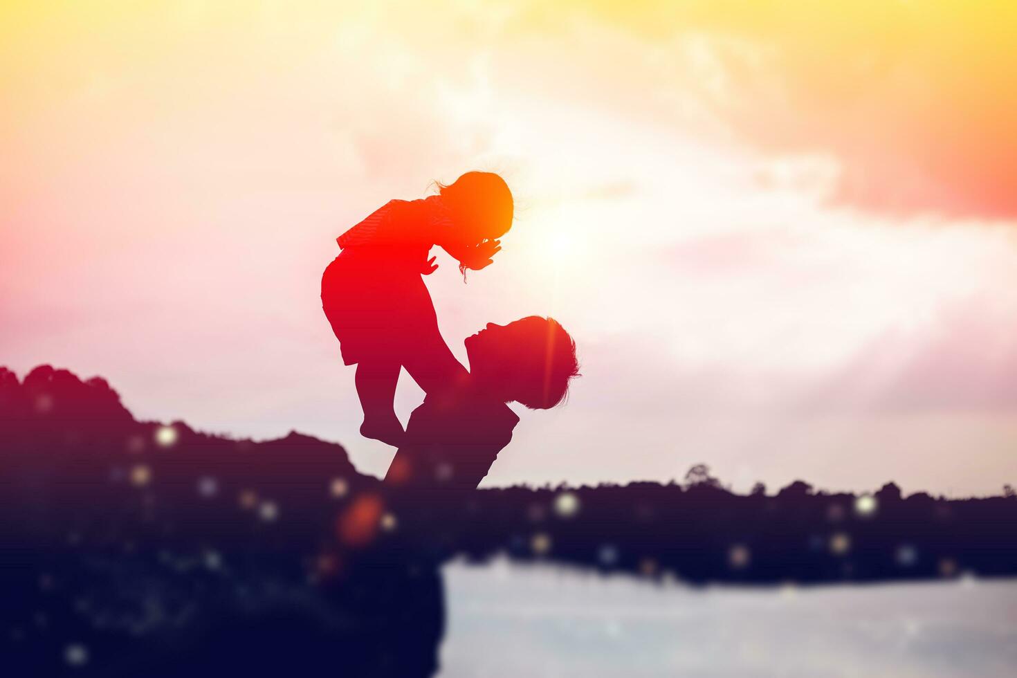 A silhouette of a happy young mother harmonious family outdoors. laughing and playing in the summer on the sunset background.SSTKHome photo