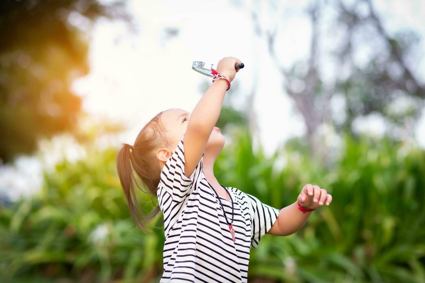 Asian little girl is using magnifying glass to play in the park.SSTKHome photo