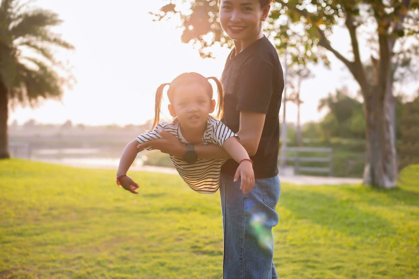 A silhouette of a happy young mother harmonious family outdoors. laughing and playing in the summer on the sunset background.SSTKHome photo