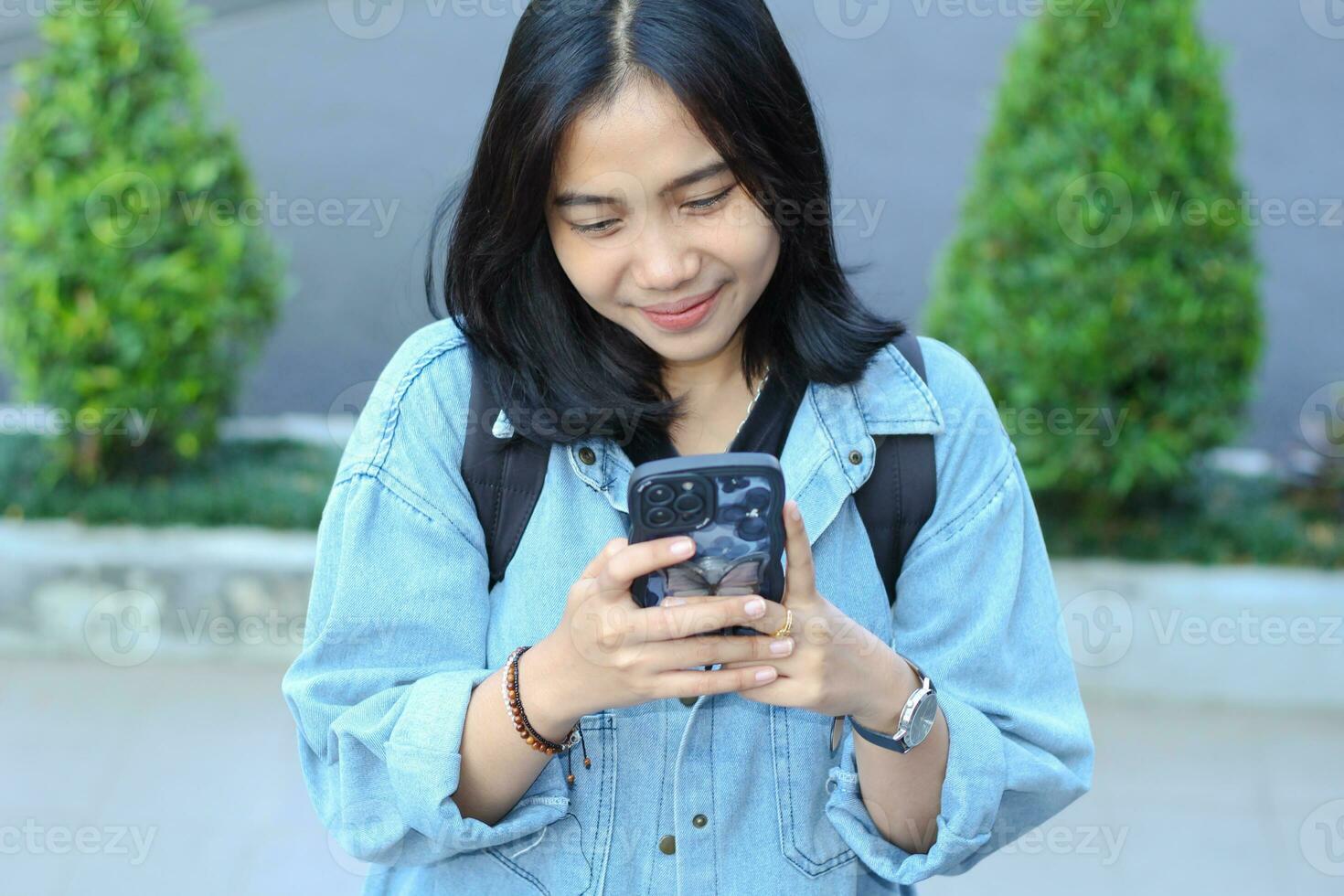 happy asian young woman enjoy using mobile app, social media, online shop, read news on smartphone, working remote or freelance video call meeting in urban staircase photo