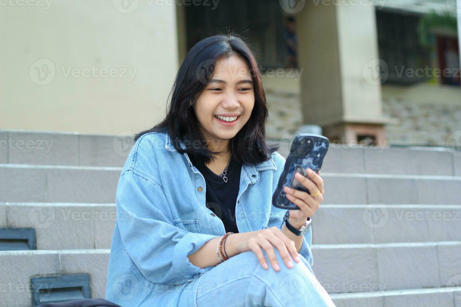 cheerful asian young woman remote worker laughing enjoy using smartphone surfing on social media, mobile app, video chatting, get online shop discount while sitting in urban stairs outdoors photo