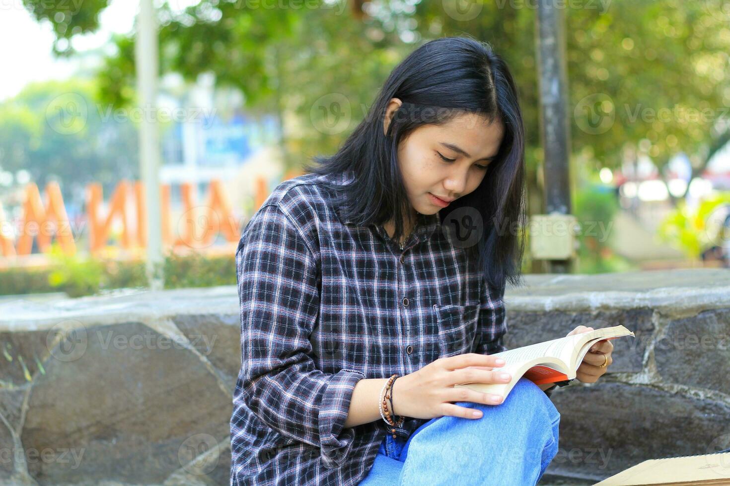 happy mindful young asian woman college student reading a book in the park, education concept photo