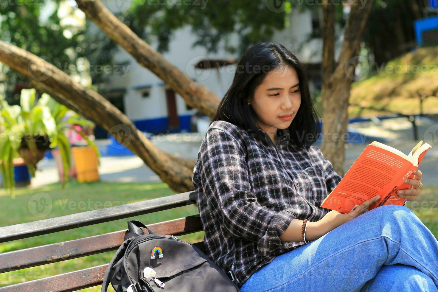 happy mindful young asian woman college student reading a book in the park, education concept photo