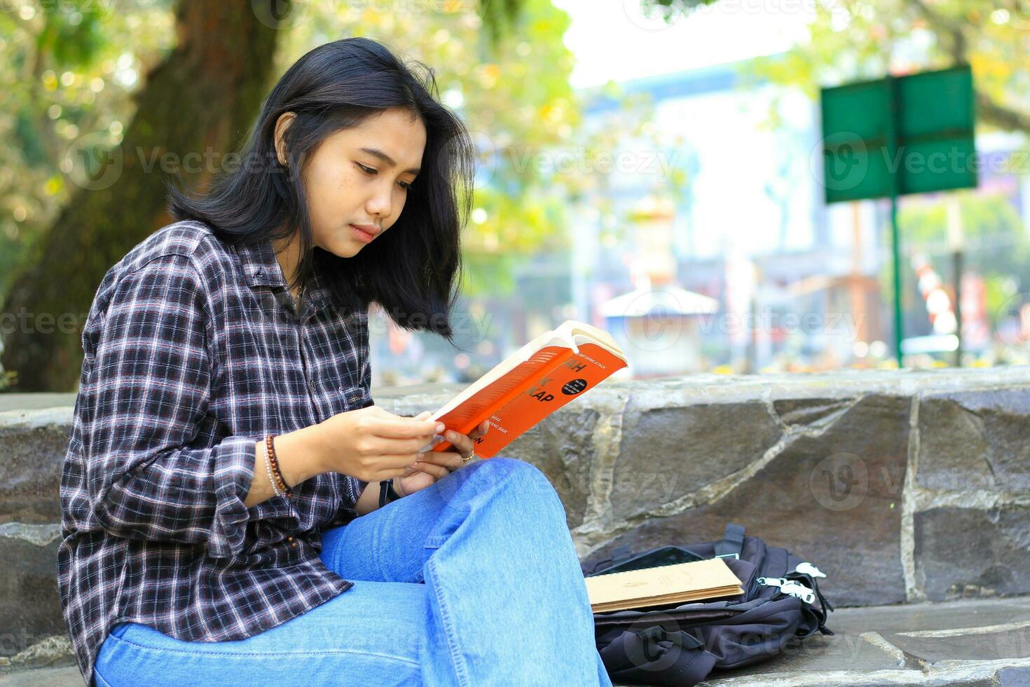 serious asian woman student read a book think and do research for her homework photo