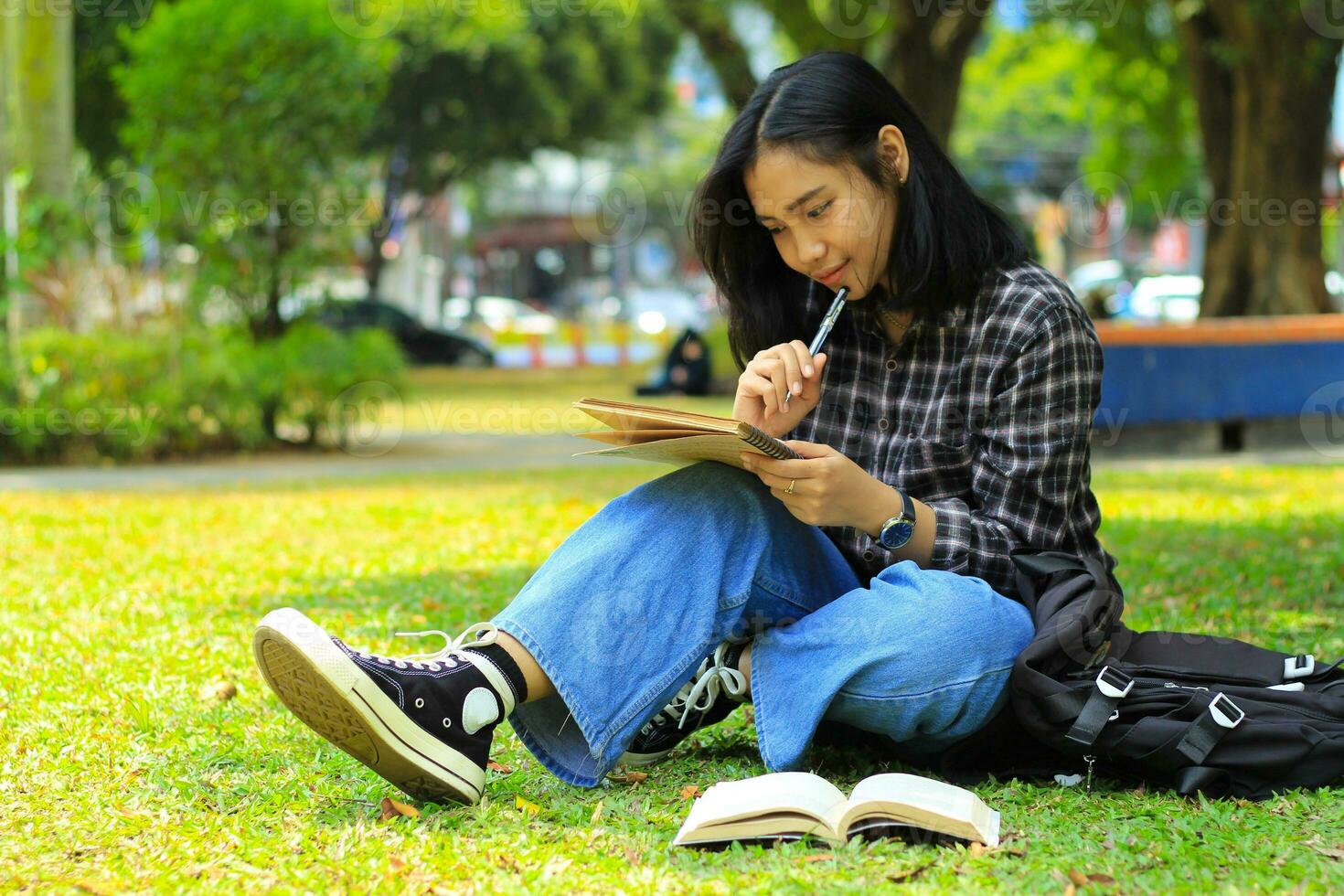 contento asiático joven mujer pensando y escritura con un bolígrafo en computadora portátil, Lista de Verificación concepto foto