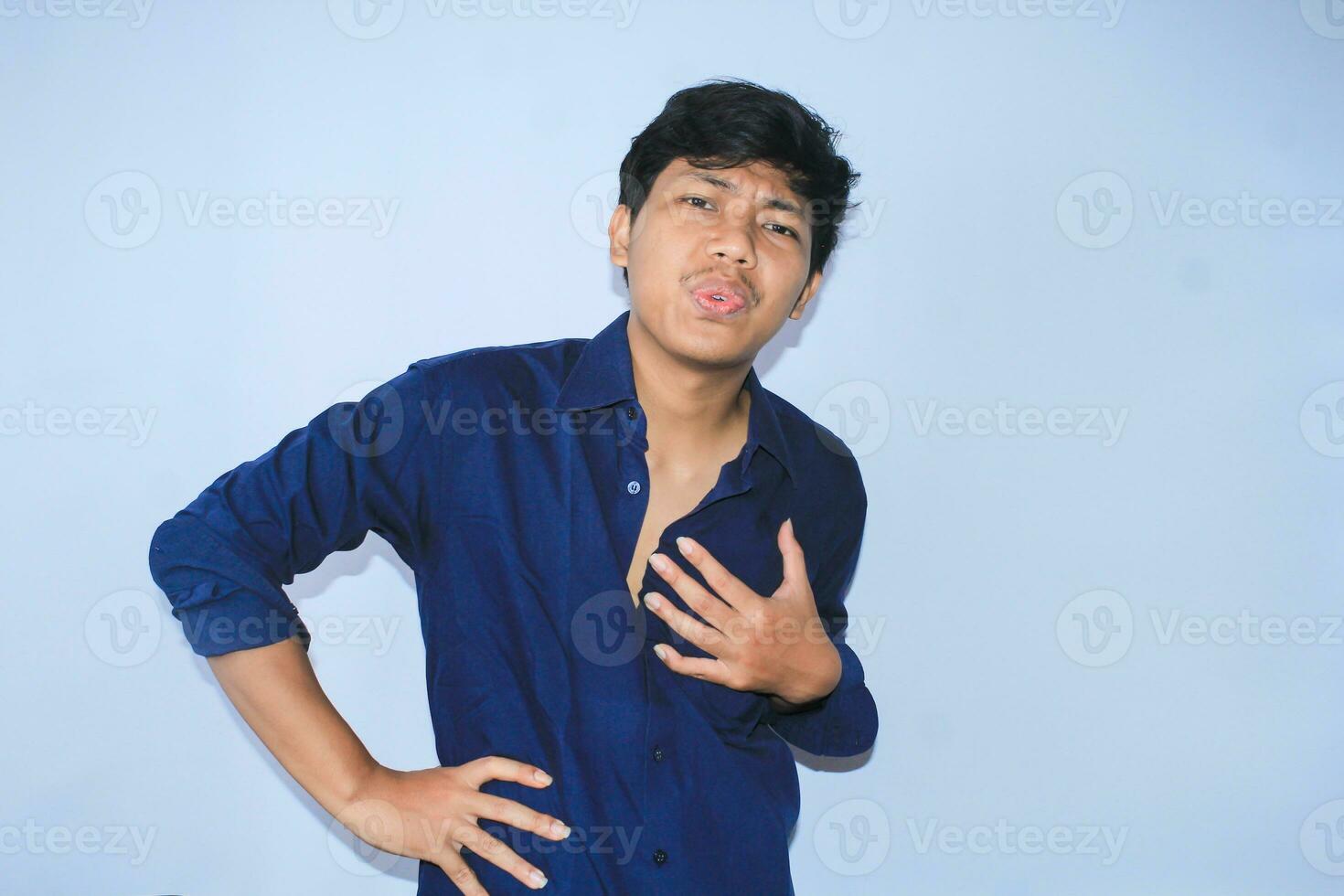 terminado hora asiático joven hombre oficina trabajador es cansado con mano en cintura y sostener su cofre obtener corazón enfermedades síntomas foto