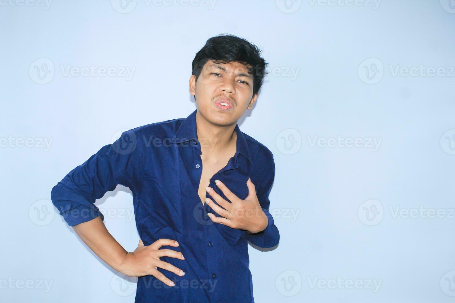 terminado hora asiático joven hombre oficina trabajador es cansado con mano en cintura y sostener su cofre obtener corazón enfermedades síntomas foto