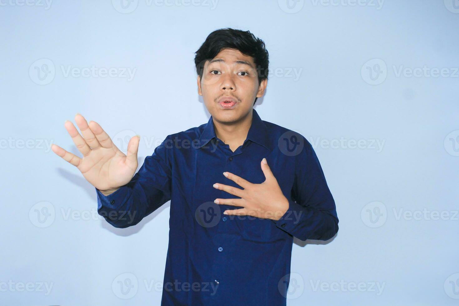 joven asiático hombre es relajante desde corazón ataque dolor haciendo inhalar y exhalando cara expresión y gesto vistiendo Armada camisa foto