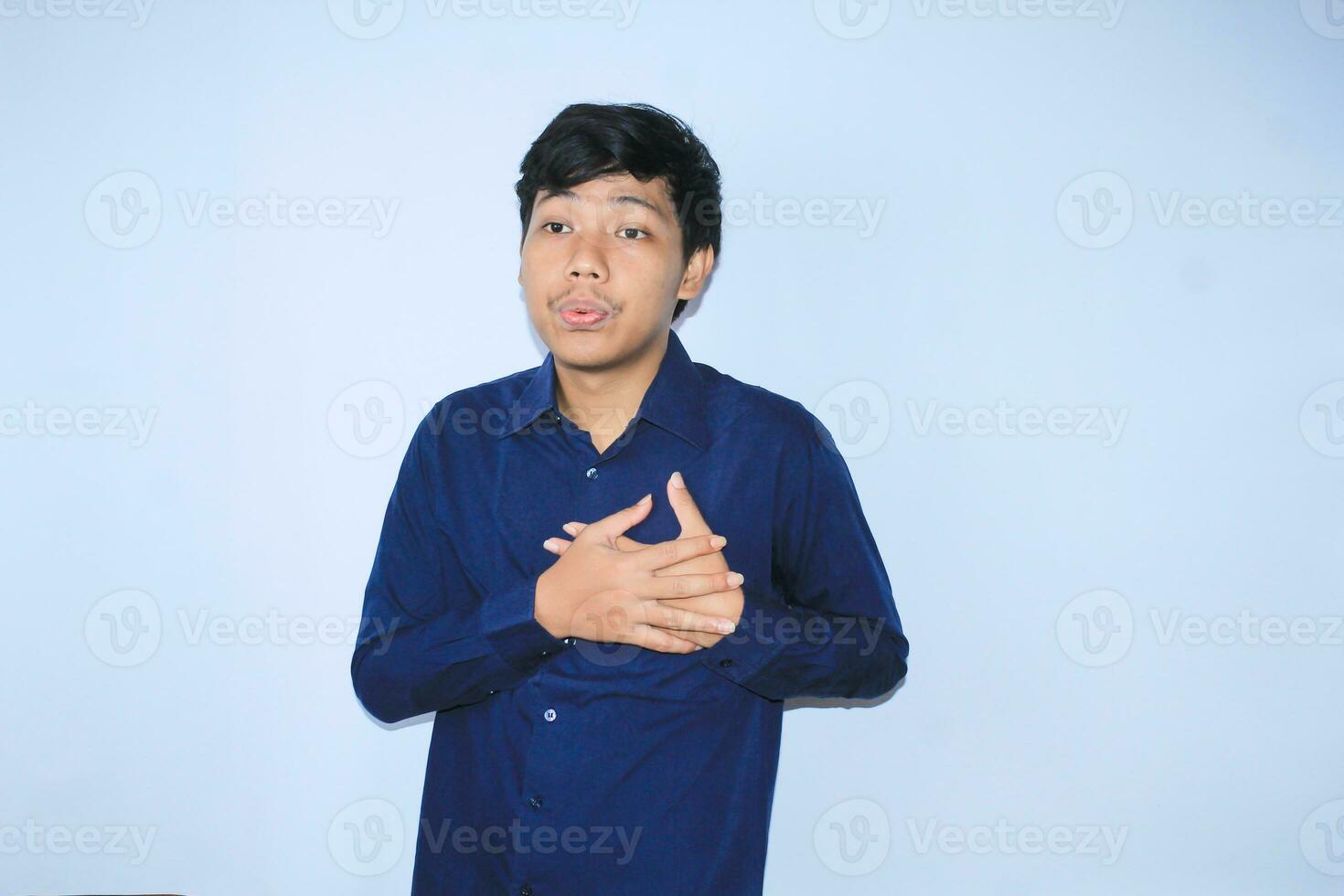 young asian man is relaxing from heart attack pain doing inhale and exhaling face expression and gesture wearing navy shirt photo