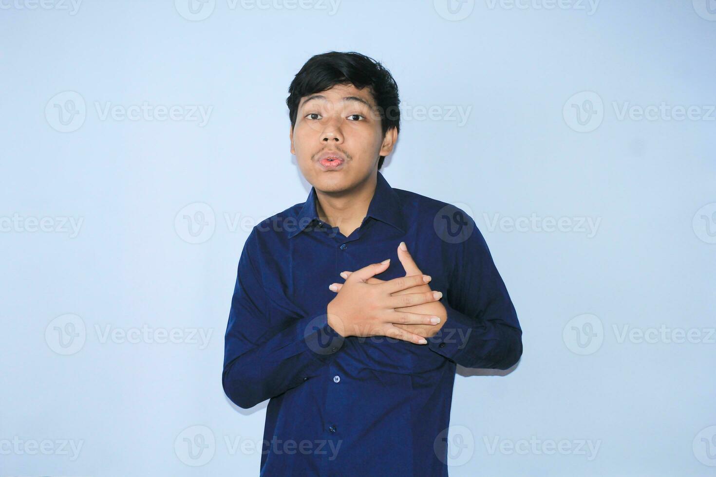 young asian man is relaxing from heart attack pain doing inhale and exhaling face expression and gesture wearing navy shirt photo