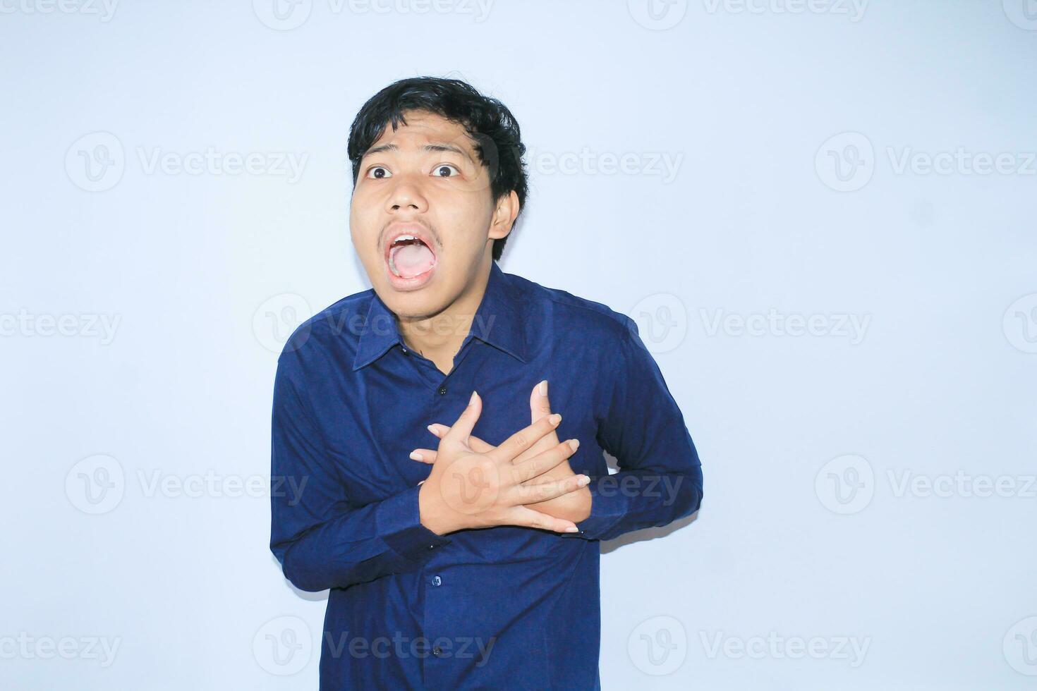 asiático hombre oficina trabajador gritando y conmovedor su cofre sufrimiento desde corazón ataque dolor vistiendo Armada camisa, aislado blanco foto