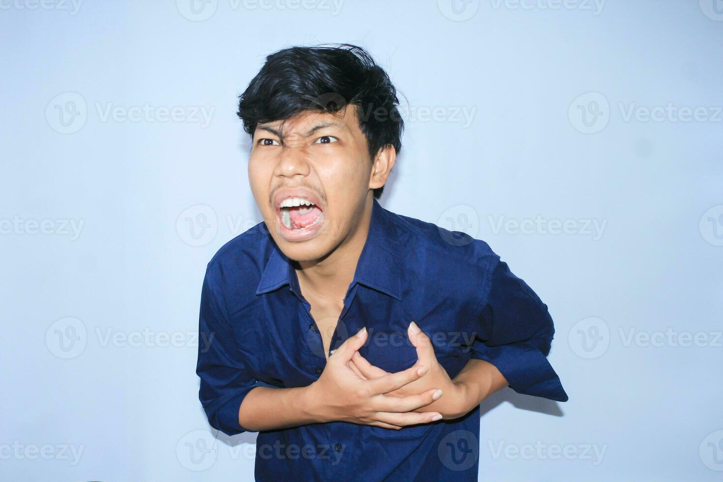 asian man office worker screaming and touching his chest suffering from heart attack pain wearing navy shirt, isolated white photo