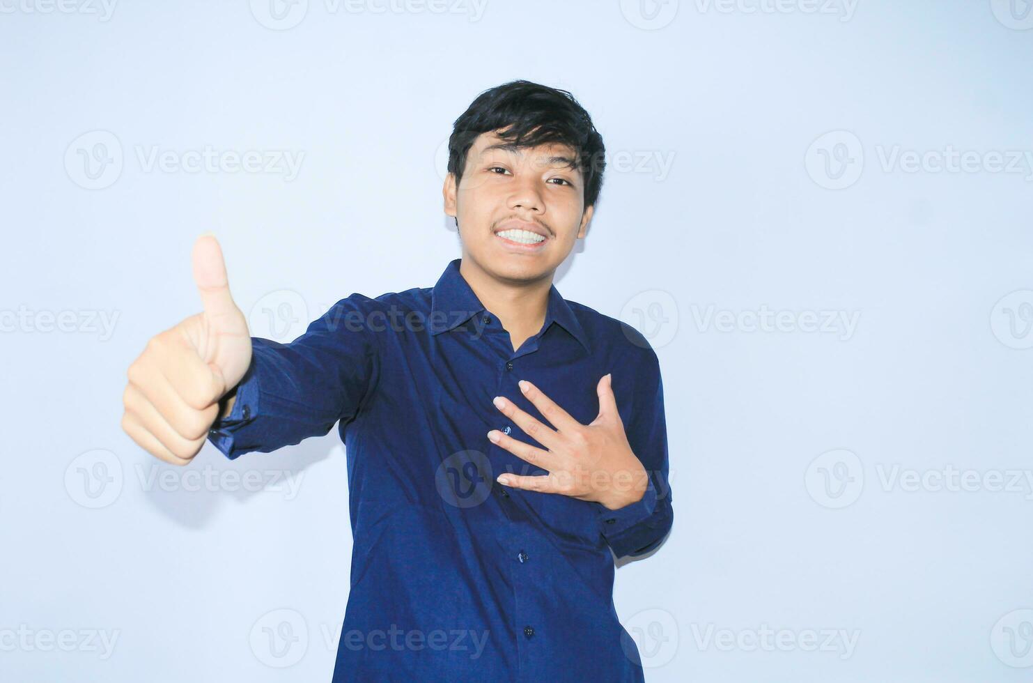 orgulloso joven asiático hombre sonriente con agradecido cara para sobrevivió desde corazón ataque y tiene recuperación es participación cofre con thunbs arriba vistiendo Armada camisa foto