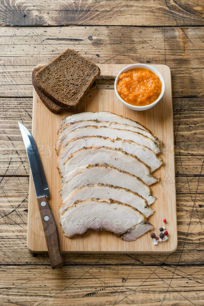 Pieces of smoked boiled pork on a wooden rustic Board with bread, sauces and spices on a wooden table photo