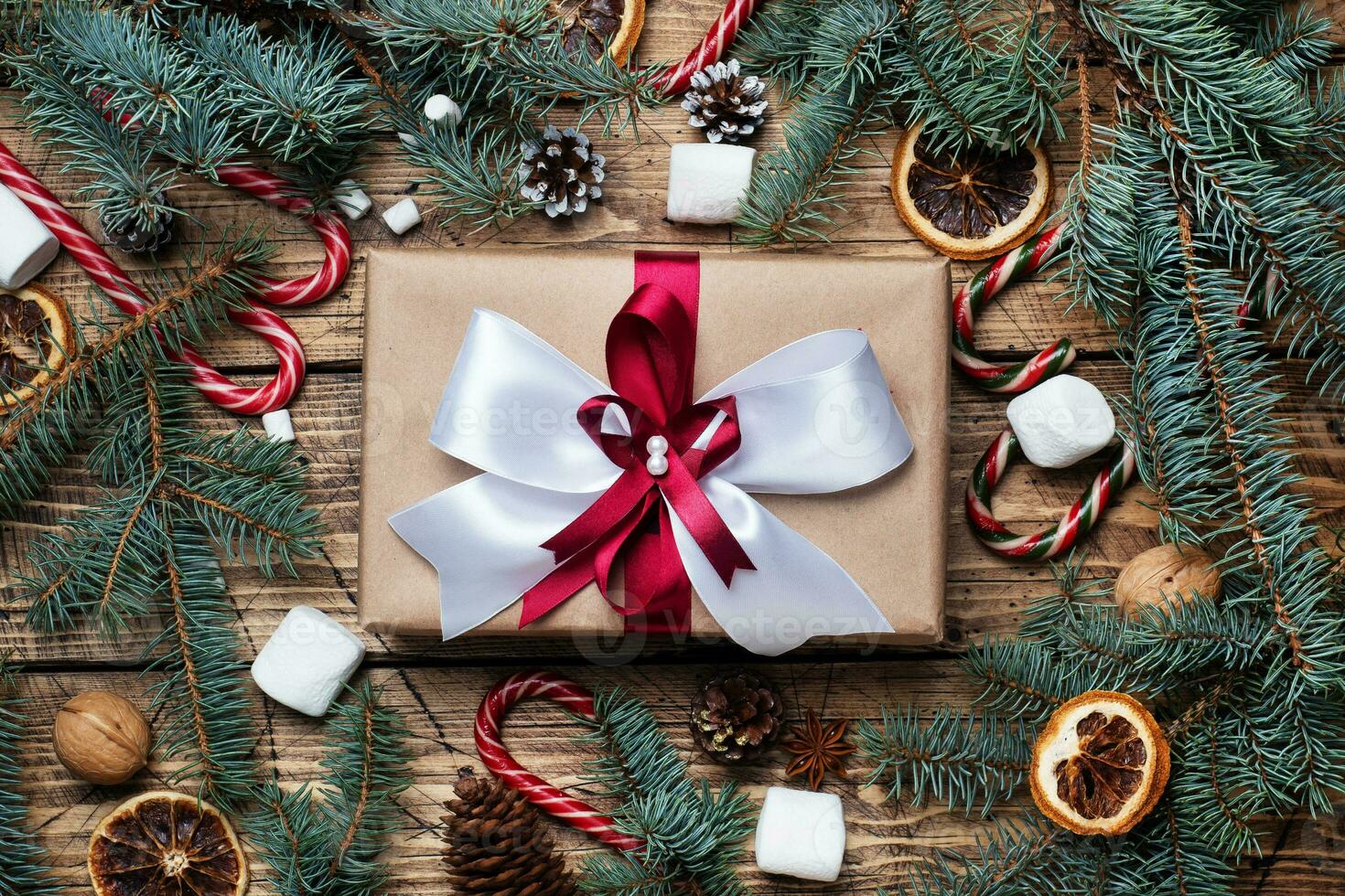 Gift box with bow. Christmas tree and decorations, cane caramel and oranges nuts Wooden background photo