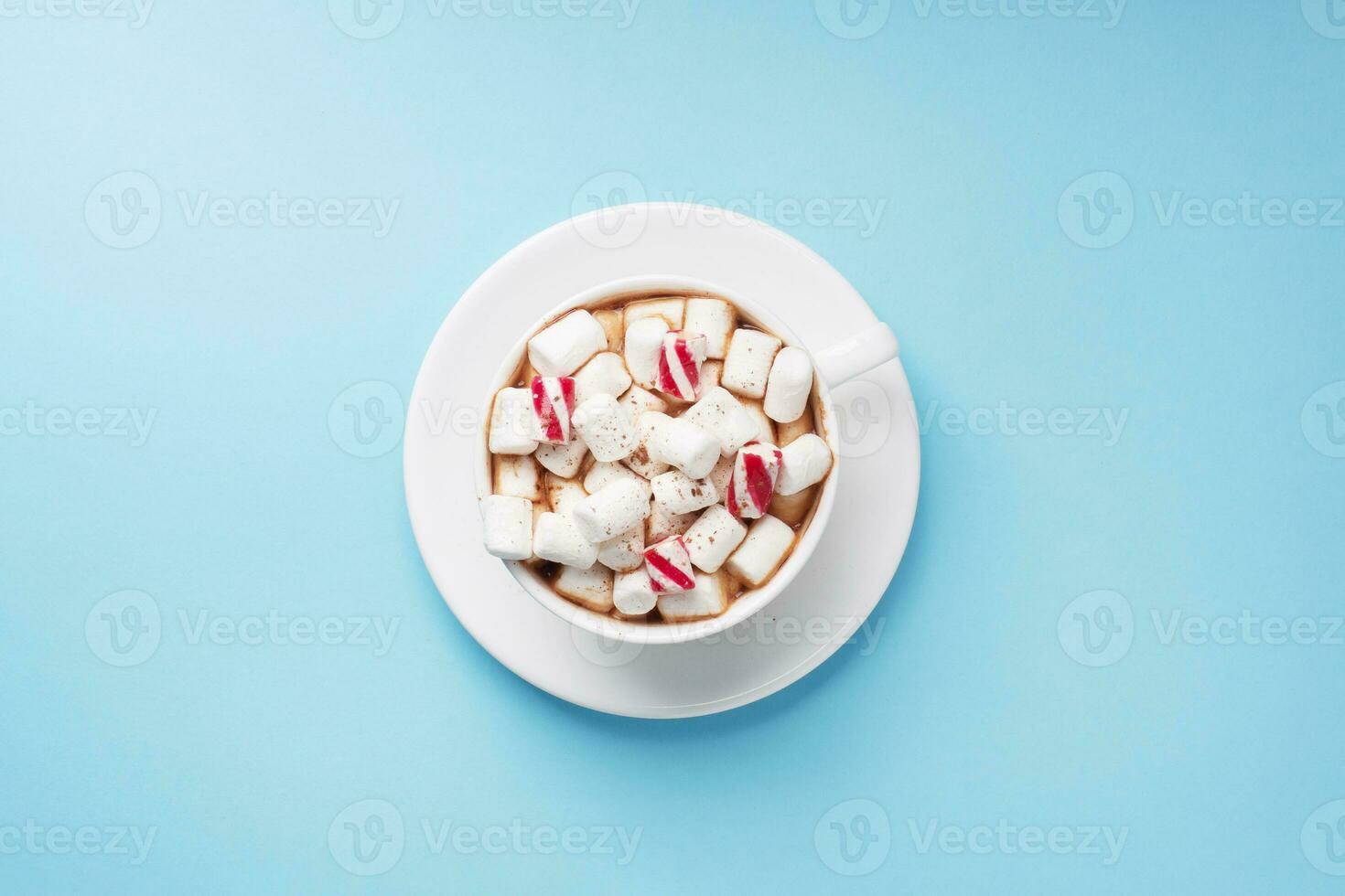 Cup of hot chocolate with marshmallow cocoa powder and caramel on pastel blue background with copy space. Christmas winter concept. photo