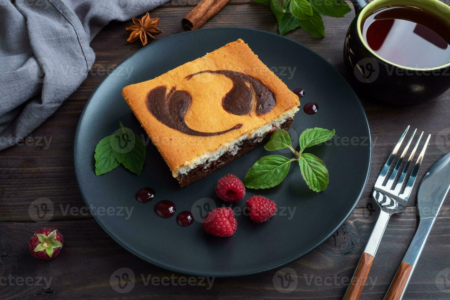 A piece of double-layer cake on a plate of chocolate brownies and curd cheesecake with raspberries. Dark background copy space photo