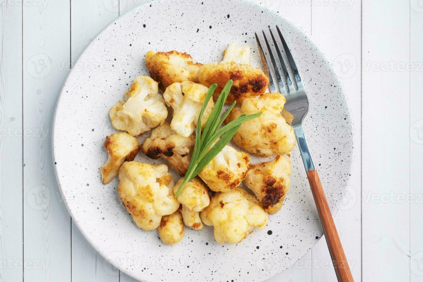 Fried cauliflower florets in batter on a white plate. White wooden background. photo