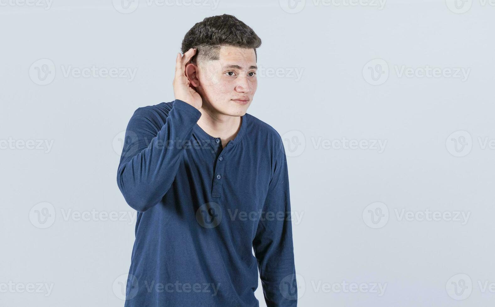 Man with hand to his ear listening to something, young man tilting his ear to listen, photo