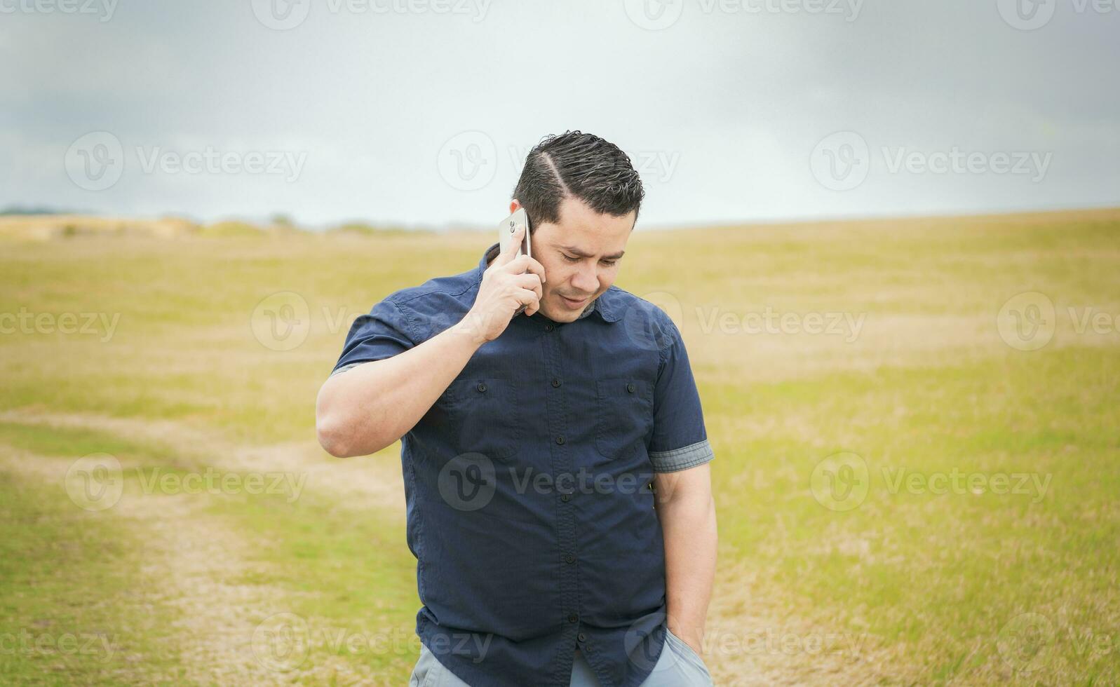 hombre vocación en el teléfono en el campo, hombre en un la carretera hablando en el teléfono, persona con su célula teléfono en el campo vocación en el teléfono, joven persona hablando en el teléfono en un campo foto