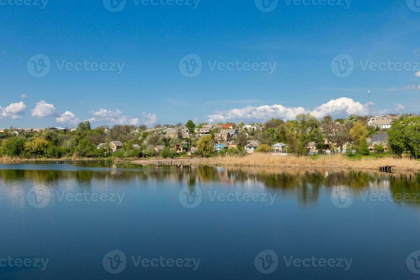green coast of a beautiful small river with white clouds in reflection photo