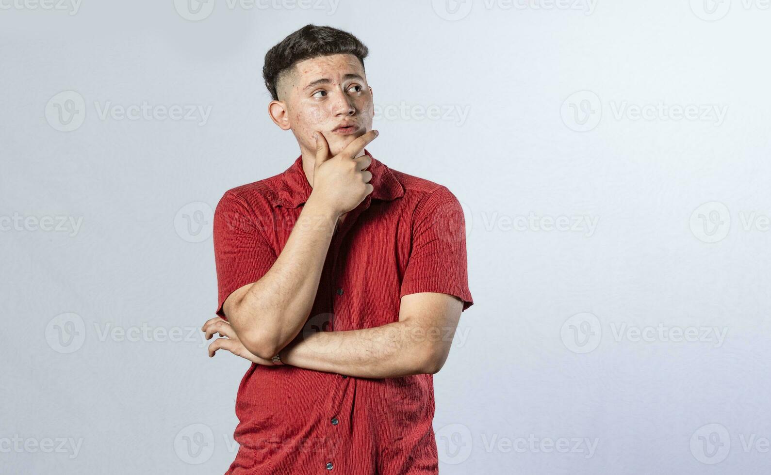 young man wondering with his hand on his chin on an isolated background, a guy thinking with his hand on his chin. photo
